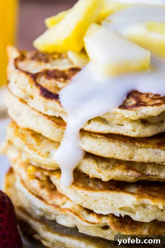 Aloha Coconut Pancake Syrup 4 a stack of banana macadamia pancakes with homemade coconut syrup and fresh pineapple on top.