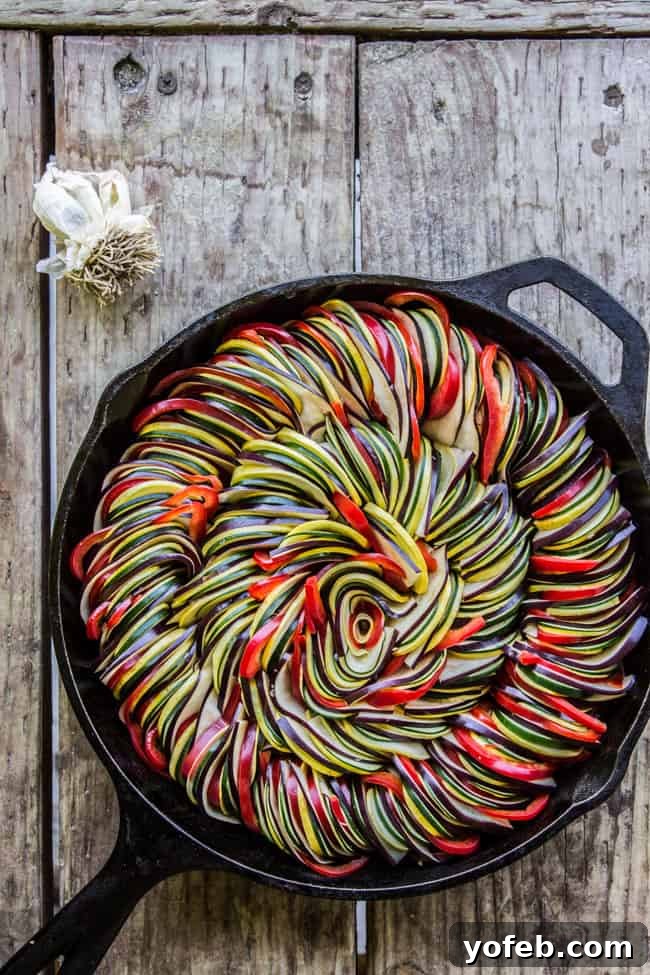 Sun-Kissed Vegetable Bake 2 Ratatouille of sliced vegetables in iron pan on wooden table.