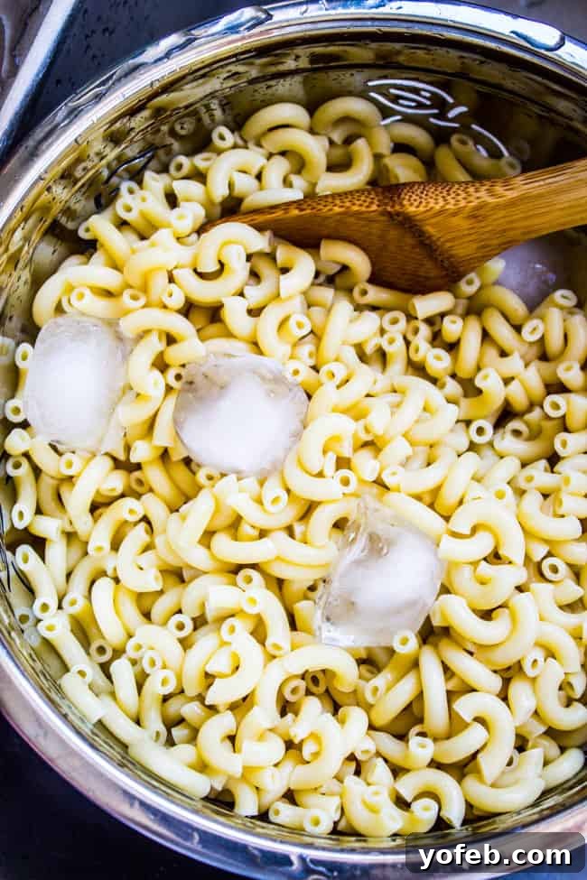 Creamy BLT Pasta Salad 5 Cooling cooked macaroni with ice cubes in a colander.