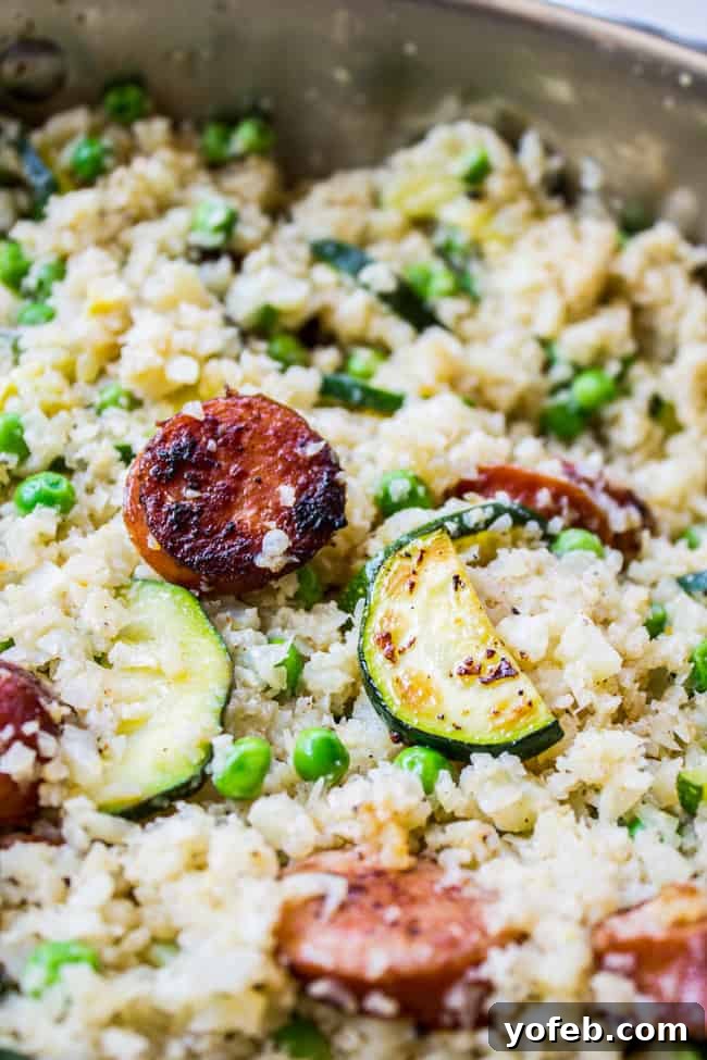 Smoky Kielbasa and Zucchini Cauliflower Rice Skillet 4 Sizzling Kielbasa and fresh Zucchini cooking in a large skillet for a healthy dinner