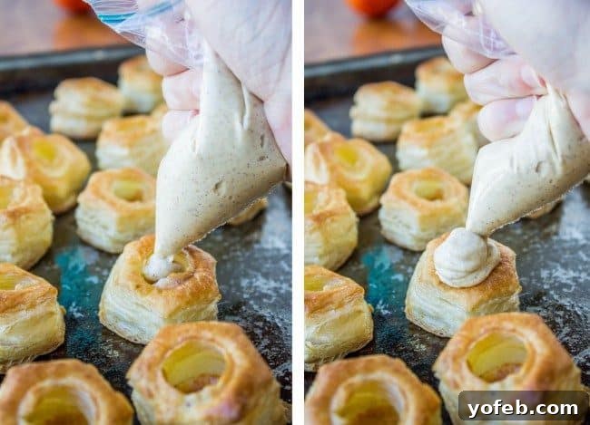 Pillowy Pumpkin Cream Cheese Puffs 3 Close-up of a hand piping creamy filling into small, round, hollow puff pastry shells on a baking tray.
