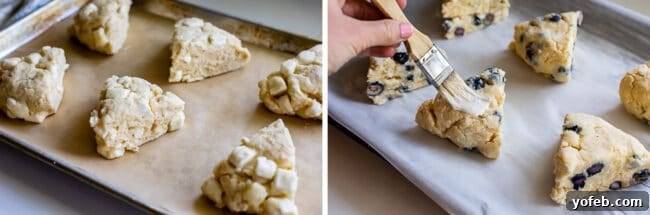 Multiple unbaked scone triangles, each with different mix-ins, neatly arranged on parchment-lined baking sheets, ready for the oven.