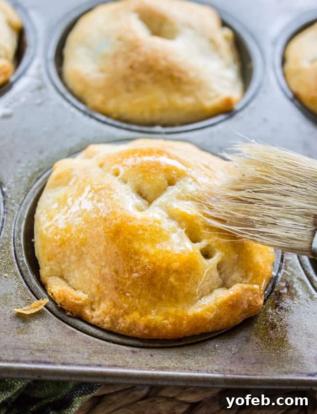 Quick Crescent Chicken Pot Pie Bites 9 Golden brown mini chicken pot pie with butter brushed on by a pastry brush.
