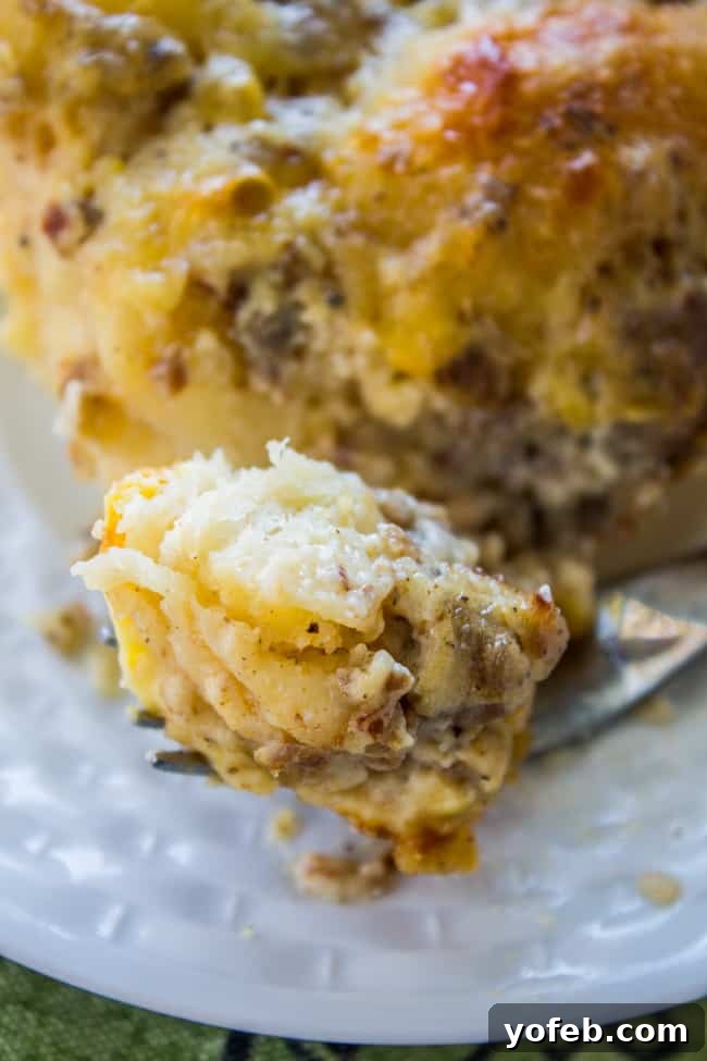 A comforting serving of Overnight Biscuits and Gravy Casserole, featuring fluffy biscuits, savory sausage gravy, and melted cheese. A slice of creamy biscuit and gravy casserole with crispy edges on a white plate, ready to be eaten.