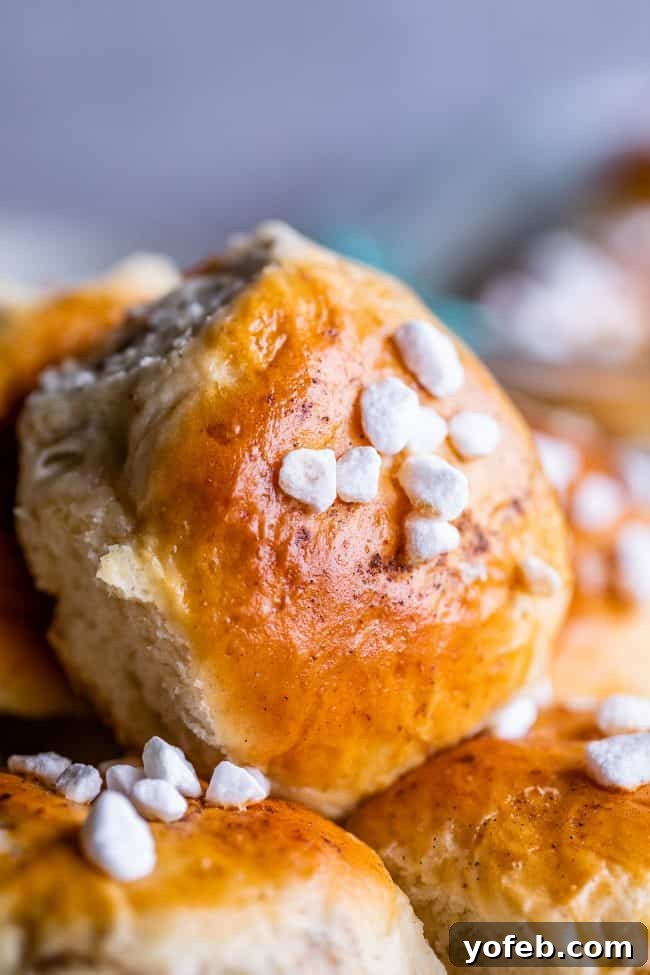 A single, perfectly baked cardamom roll featuring a golden crust and sparkling pearl sugar. The soft, airy texture of the roll is visible, inviting a taste.