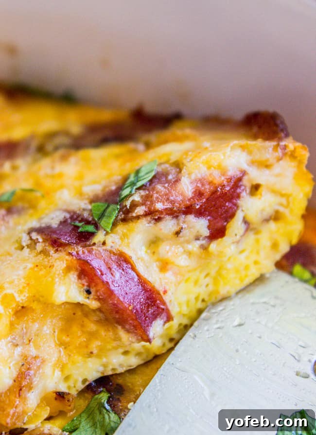 Serving a Perfect Slice of Overnight Egg Casserole Spatula lifting a section of golden scrambled egg casserole, ready to serve