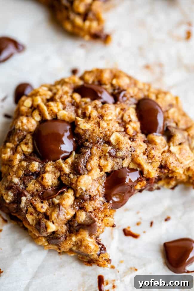 Wholesome Chocolate Chip Delights 5 Healthy cookies cooling on a baking sheet, with one cookie showing a bite taken out, revealing its soft interior.