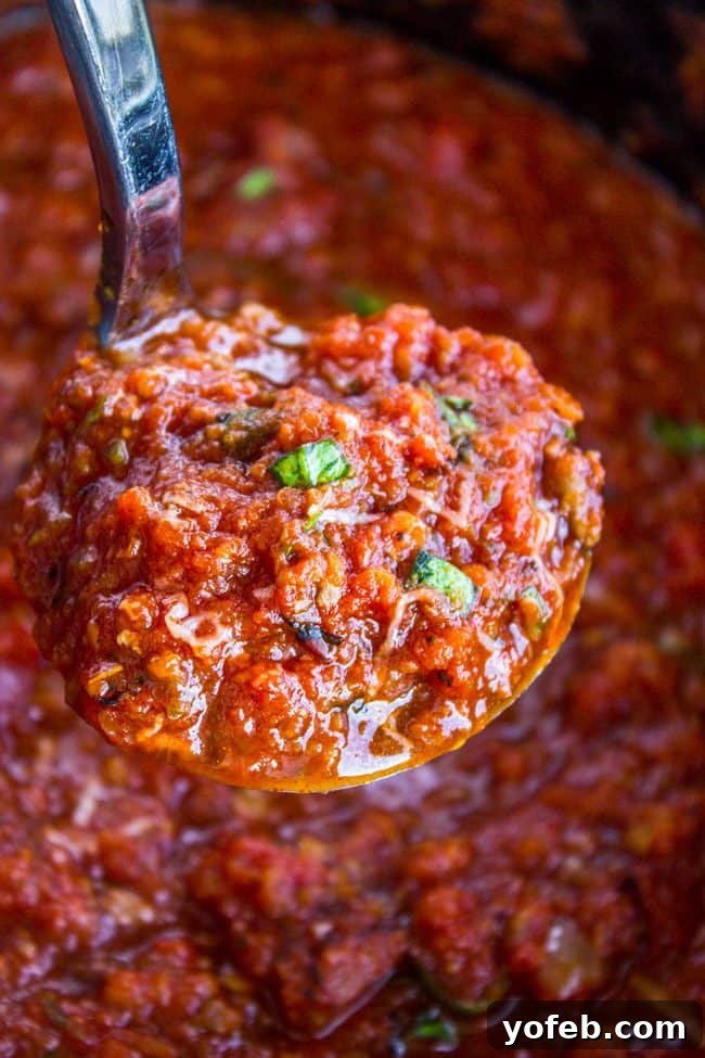 Effortless Slow Cooker Pasta Sauce 2 Slow cooker spaghetti sauce with Italian sausage being lifted with a ladle.