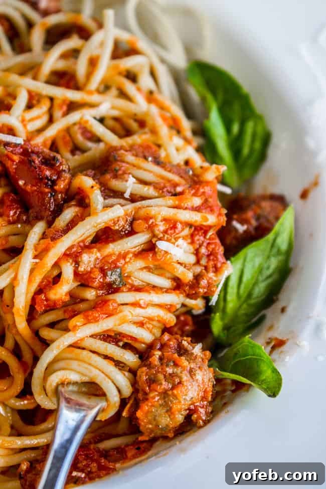 Effortless Slow Cooker Pasta Sauce 3 Spaghetti sauce served over pasta with fresh basil, twirled on a fork.