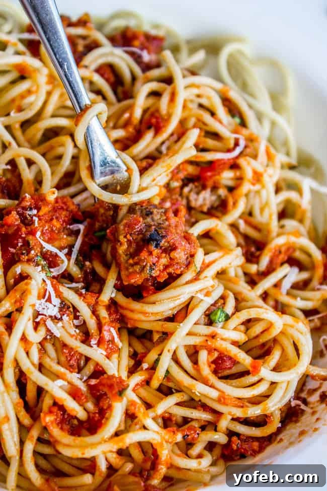 Effortless Slow Cooker Pasta Sauce 9 spaghetti sauce with Italian sausage served over spaghetti with a fork.