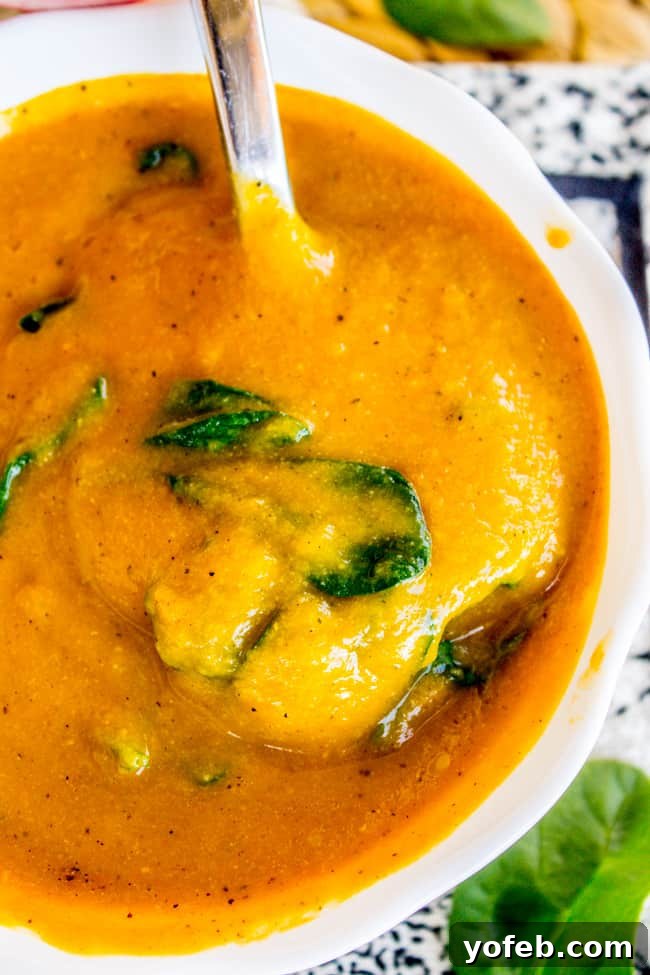 Creamy Vegan Cauliflower Soup 13 creamy cauliflower soup in a white bowl with a spoon.