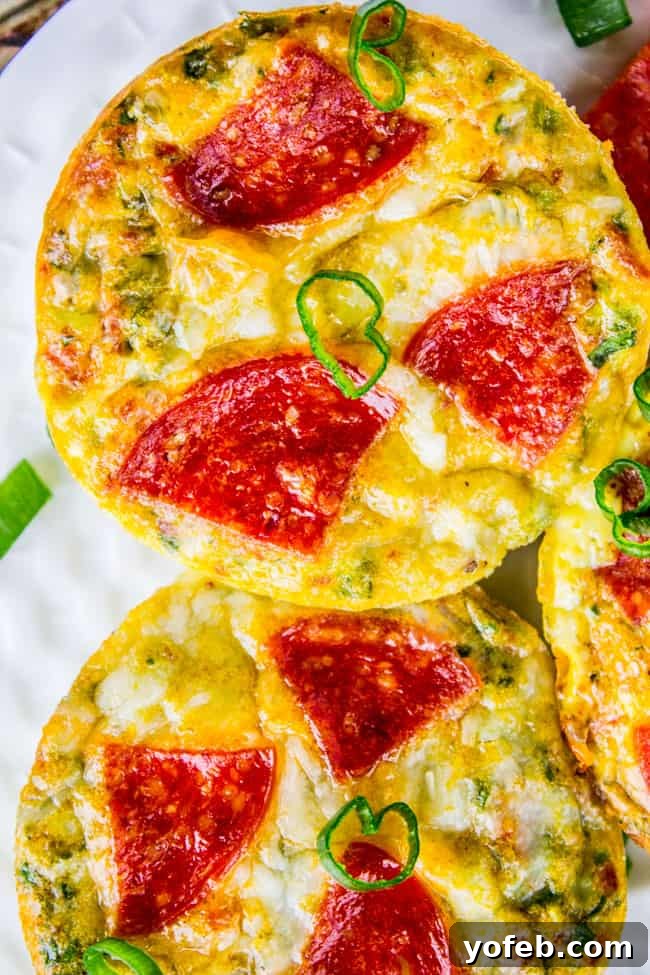 Pizza Egg Muffins: Effortless Weekday Breakfast 2 Perfectly round Pizza Egg Muffins, golden brown with visible pepperoni, on a white plate, ready to eat.