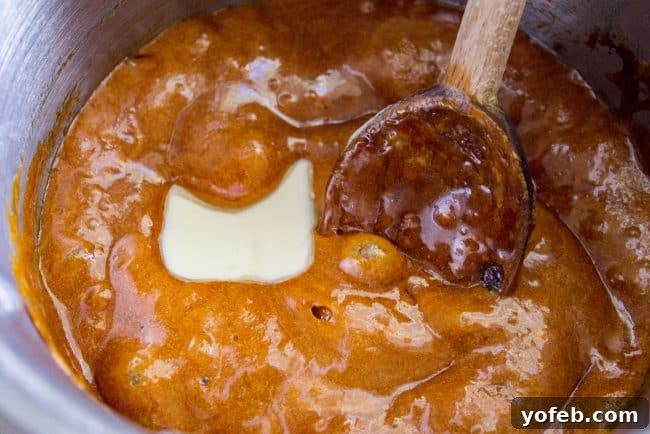 Crafting delicious homemade caramel sauce in a pot – a simple process for the perfect topping for your pumpkin cheesecake. A saucepan on a stovetop with golden, bubbling caramel sauce being made, illustrating the easy caramel preparation process.