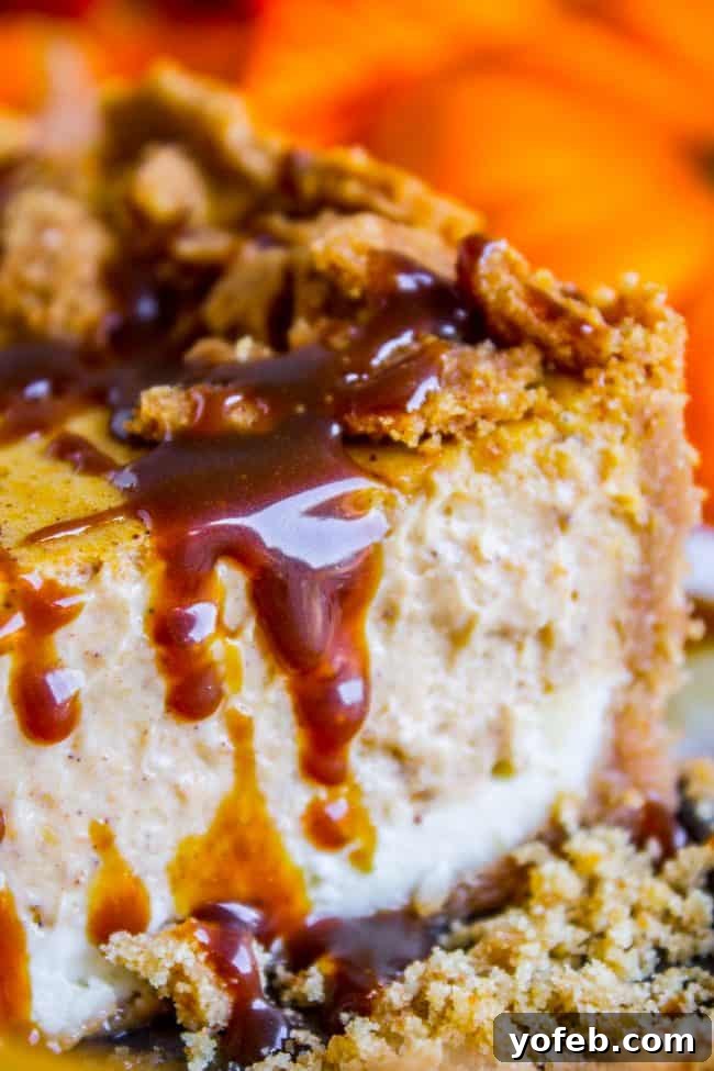Indulge in this Layered Pumpkin Cheesecake, a decadent and impressive dessert with a buttery crust, smooth vanilla, and spiced pumpkin layers. #easy #recipe #pumpkin #fall #fallbaking #cheesecake #creamcheese #caramel #grahamcracker #crust #baked #best #saltedcaramel #fromscratch #homemade A close-up of a double layer pumpkin cheesecake slice, highlighting the creamy texture, two distinct layers, and generous caramel drizzle.