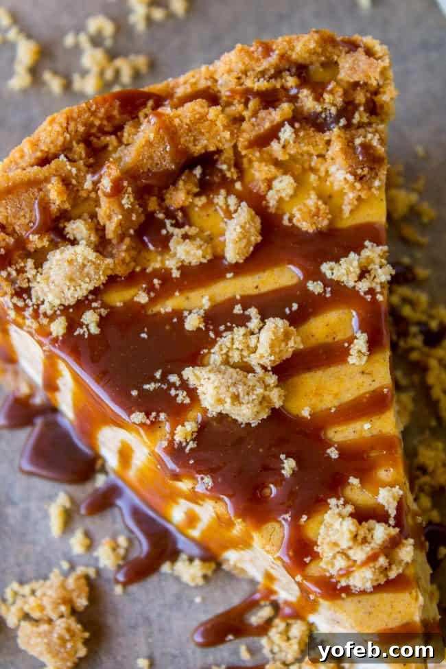 Discover the perfect Thanksgiving dessert: a two-layer pumpkin cheesecake with vanilla and spiced pumpkin, creamy and delicious. #easy #recipe #pumpkin #fall #fallbaking #cheesecake #creamcheese #caramel #grahamcracker #crust #baked #best #saltedcaramel #fromscratch #homemade A tempting slice of pumpkin cheesecake topped with caramel and graham cracker crumbles, ready for a dessert lover.