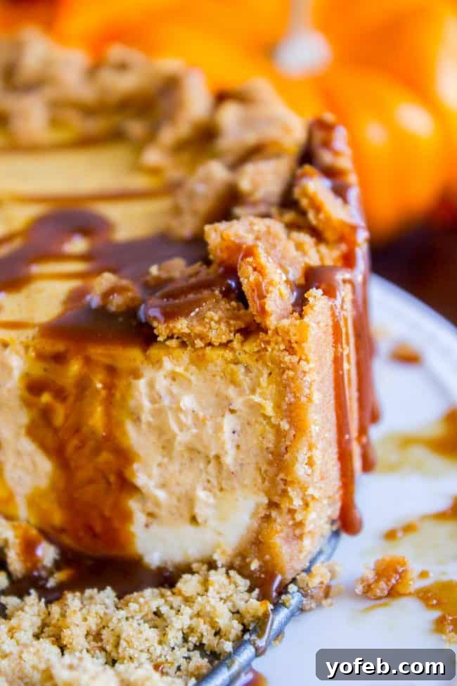 The ultimate autumn delight: Double Layer Pumpkin Cheesecake with a golden graham cracker crust and luscious caramel topping. #easy #recipe #pumpkin #fall #fallbaking #cheesecake #creamcheese #caramel #grahamcracker #crust #baked #best #saltedcaramel #fromscratch #homemade A perfect slice of double layer pumpkin cheesecake, featuring the distinct vanilla and pumpkin layers on a crunchy graham cracker crust, topped with homemade caramel.