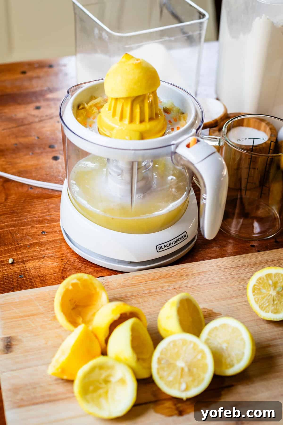Seriously Zesty Lemon Bars My Absolute Best 14 lemon on an electric juicer with several lemon halves on a cutting board.