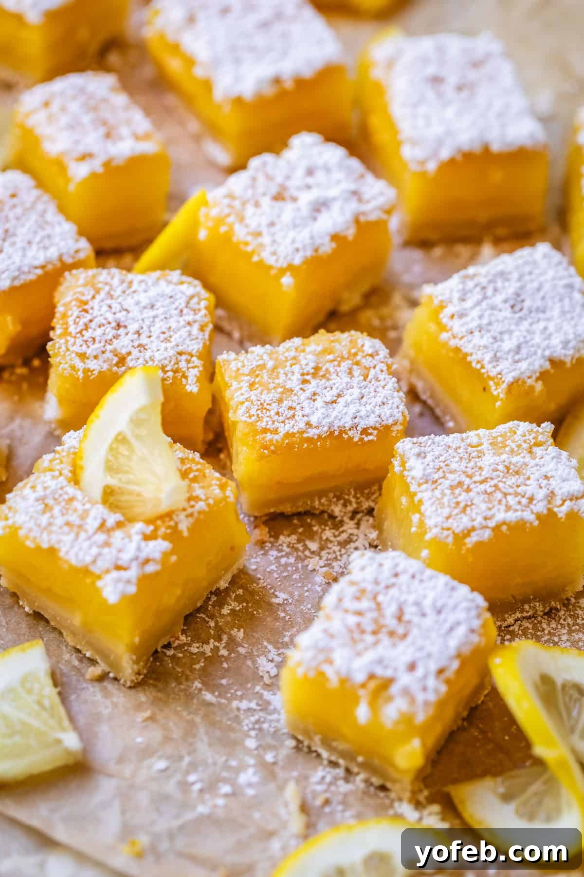 Seriously Zesty Lemon Bars My Absolute Best 23 several lemon bar squares dusted with powdered sugar on parchment paper.