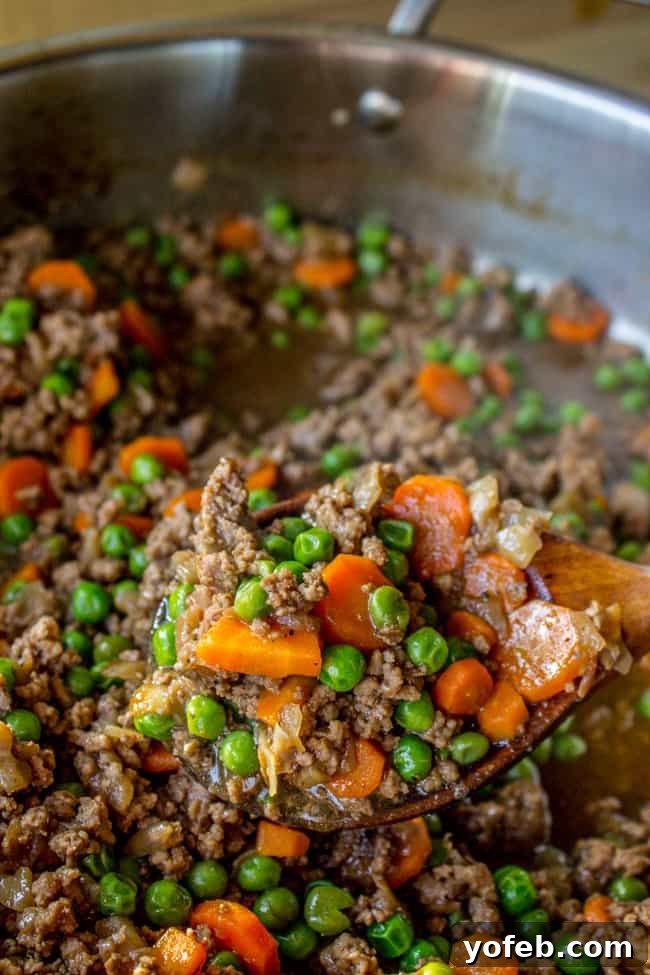 Ultimate Cheesy Shepherds Pie 6 cooking peas, carrots, and onions with ground beef in a skillet, for the pie filling.