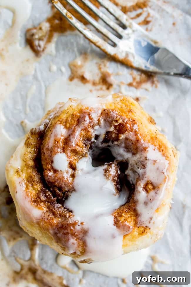 Quick No Yeast Cinnamon Rolls 5 A close-up of a flaky cinnamon roll with a fork nearby, showcasing its tender layers and delicious icing.
