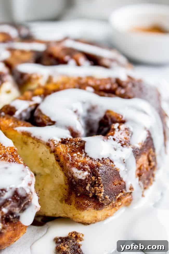 Quick No Yeast Cinnamon Rolls 10 Flaky cinnamon rolls gently pulled apart, revealing their tender layers, with generous icing drizzled on top.