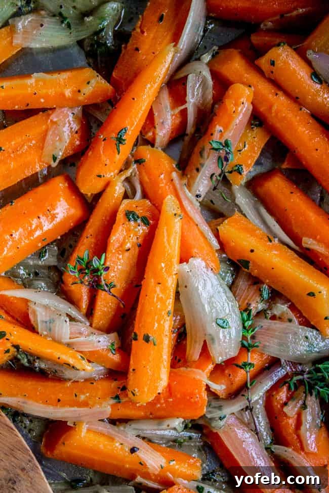 Thyme-Infused Sautéed Carrots and Shallots 2 Close-up of golden brown sautéed carrots and shallots with fresh thyme in a serving dish.
