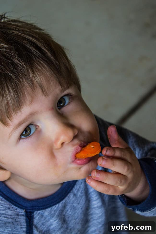Thyme-Infused Sautéed Carrots and Shallots 5 A young boy enthusiastically eating a sauteed carrot, showing it's kid-approved.