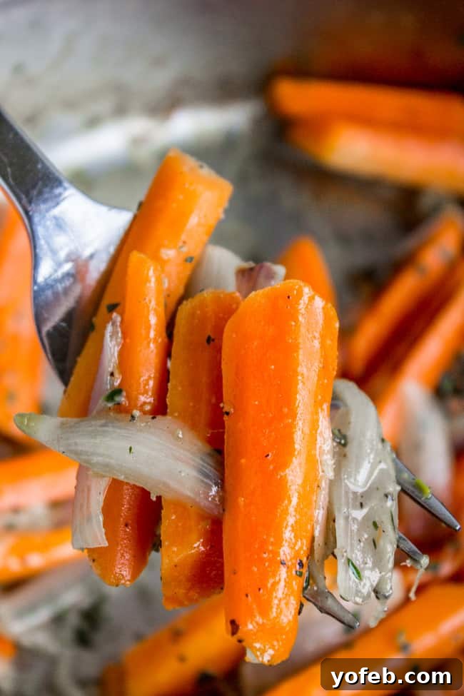Thyme-Infused Sautéed Carrots and Shallots 6 A fork lifts a handful of golden-brown sautéed carrots and shallots from a serving bowl.