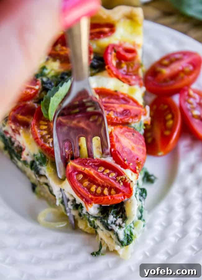 Farmers Market Quiche with Cherry Tomatoes Leeks and Spinach 5 A slice of Cherry Tomato, Leek, and Spinach Quiche, highlighting the flaky crust and filling.