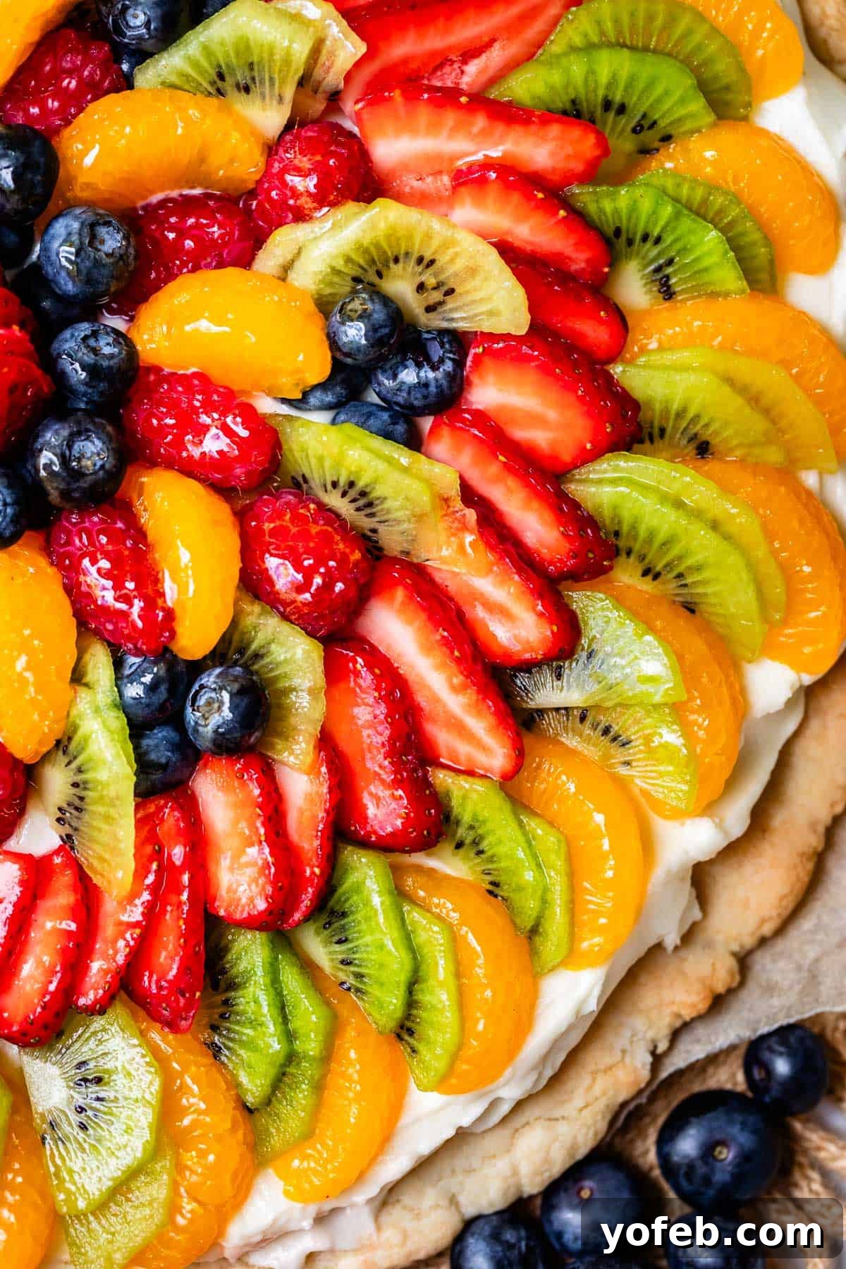 Pillowy Sugar Cookie Fruit Pizza Delight 23 Close-up view of a fruit pizza on a circular crust, highlighting the vibrant layers of fresh fruit, creamy frosting, and soft cookie base.