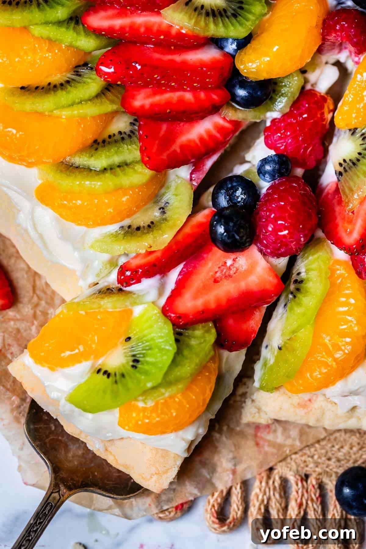 Pillowy Sugar Cookie Fruit Pizza Delight 24 A serving spatula removing a perfectly cut slice of Sugar Cookie Fruit Pizza from the whole dessert, showcasing its layers.