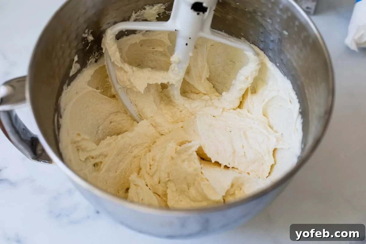 Pillowy Sugar Cookie Fruit Pizza Delight 10 Creamed butter and cream cheese mixture in a metal mixing bowl with a paddle attachment, light and fluffy.