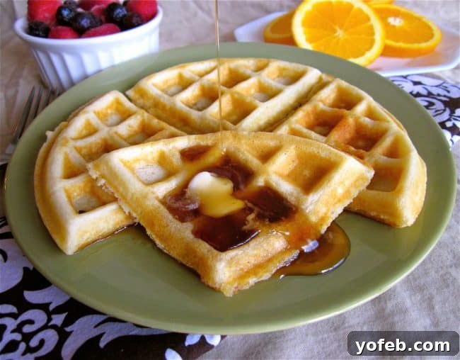 Homemade Waffle Perfection 2 An older photo showing a homemade waffle on a plate with butter and syrup, with fresh fruit blurred in the background.