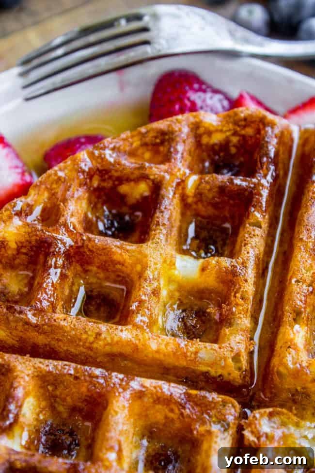Fresh Strawberry Waffles for a Delicious Breakfast A plate of golden homemade waffles adorned with fresh strawberries and a drizzle of syrup.