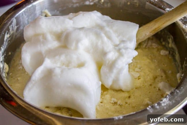 Folding Egg Whites into Waffle Batter for Fluffiness Expertly folding whipped egg whites into waffle batter, creating a light and airy consistency.