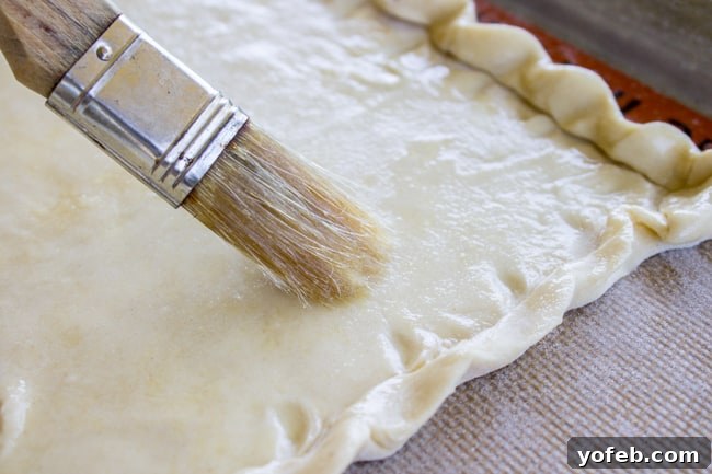 Peachy Nutella Pockets 7 A pastry brush spreading melted butter over puff pastry.