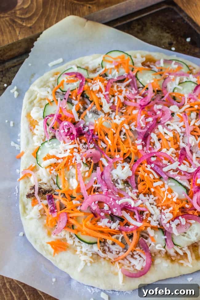 Tangy Thai Zucchini Pizza with Pickled Red Onions 6 Thai pizza prepared on parchment paper, showcasing fresh zucchini, carrots, and meat before baking