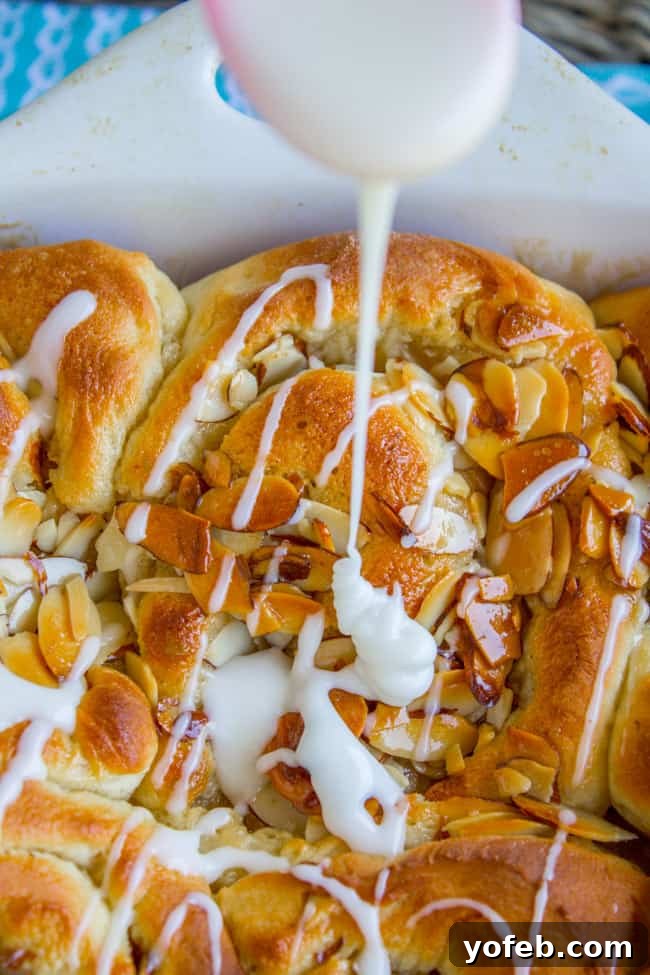 Golden Hour Almond Swirls 2 Golden brown honey almond rolls with crunchy almond topping and a generous drizzle of sweet glaze.