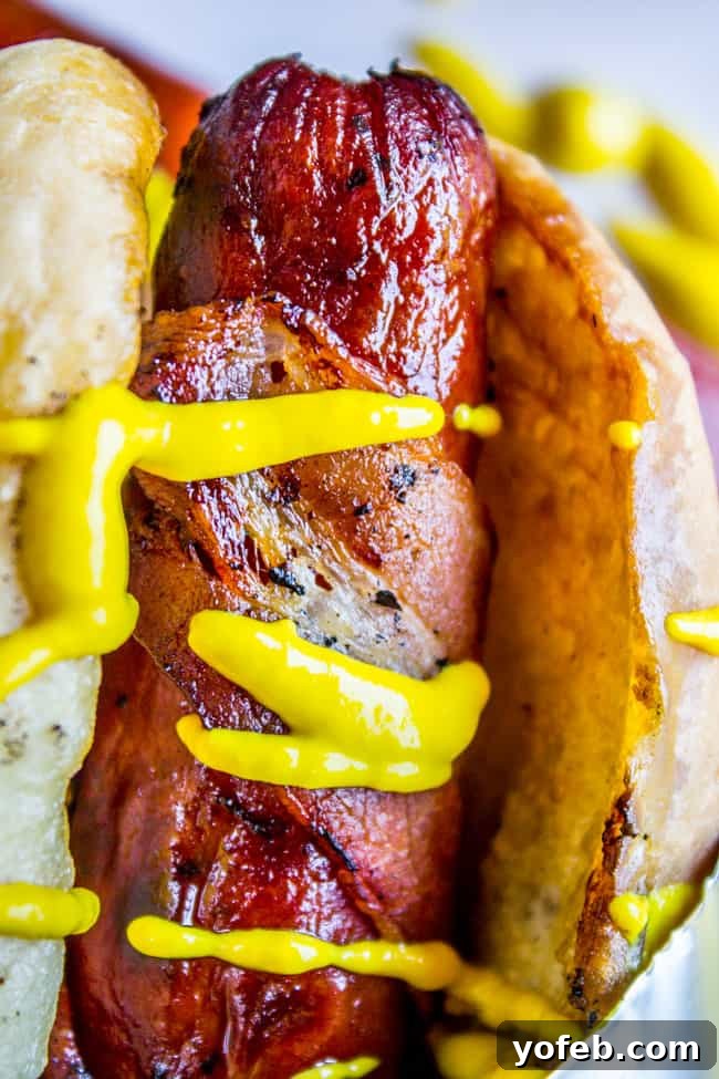 Crispy Bacon-Wrapped Grilled Hot Dogs 2 Perfectly Grilled Bacon Wrapped Hot Dogs with Sautéed Onions and Peppers