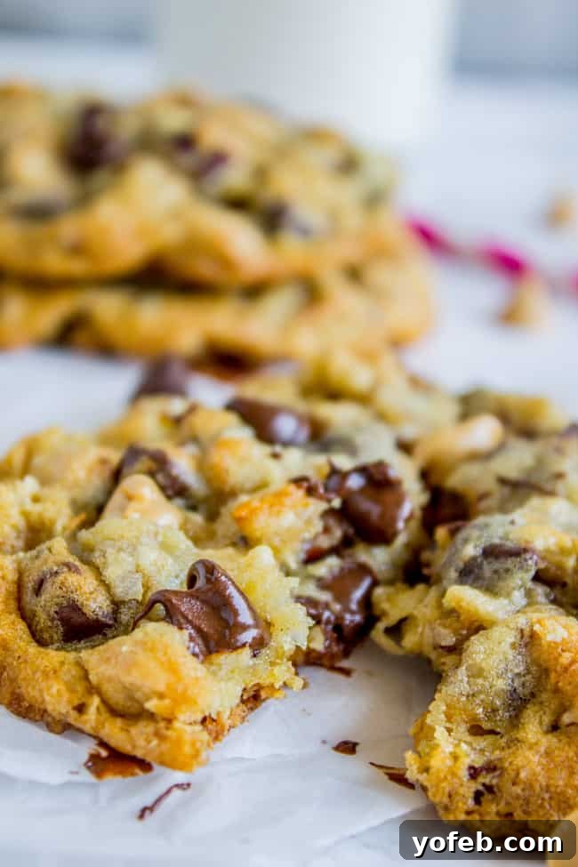 Texas Cowboy Cookies from The Food Charlatan. Everything's bigger in Texas and these Cowboy cookies (sometimes called Texas Cow Chips) are no exception. They are crispy on the edges but chewy and moist in the middle, and have about a hundred mix-ins that all combine to create the Texas of all cookies. #texas #cowboy #cookies #chocolatechip #chocolate #peanutbutterchips #oatmeal #coconut #pecans #crispy #crunchy A close-up of a cowboy cookie split in half, revealing its rich texture and abundant mix-ins.