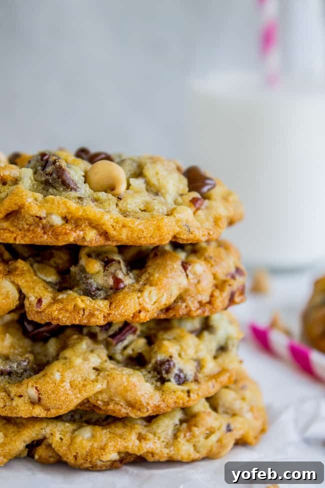 Texas Cowboy Cookies from The Food Charlatan. Everything's bigger in Texas and these Cowboy cookies (sometimes called Texas Cow Chips) are no exception. They are crispy on the edges but chewy and moist in the middle, and have about a hundred mix-ins that all combine to create the Texas of all cookies. #texas #cowboy #cookies #chocolatechip #chocolate #peanutbutterchips #oatmeal #coconut #pecans #crispy #crunchy A beautifully stacked tower of golden-brown cowboy cookies, ready to be enjoyed.