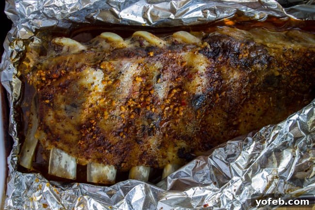 Nana's Irresistible Fall-Off-The-Bone Ribs with Barb's Signature Barbecue Sauce 8 Slow-roasted pork ribs, removed from the oven and unwrapped, sitting on a baking sheet before being grilled.