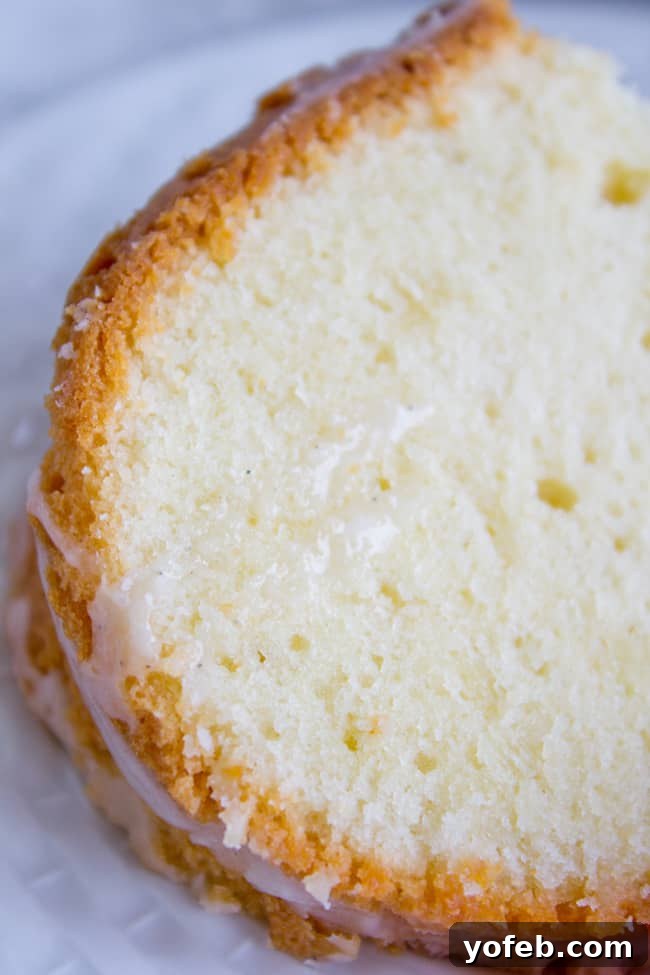 The Ultimate Cream Cheese Pound Cake 3 A close-up of a generous slice of cream cheese pound cake, glistening with vanilla glaze, highlighting its moist, tender crumb.