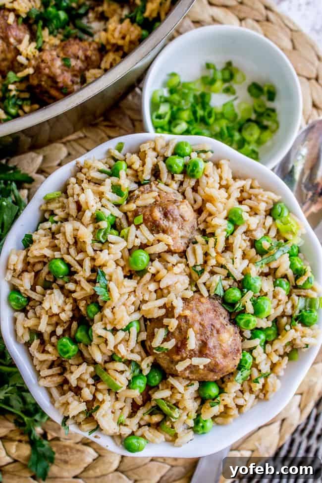 One Pan Meatball Rice Feast 3 Hearty meatballs with rice and peas served in a pristine white bowl.