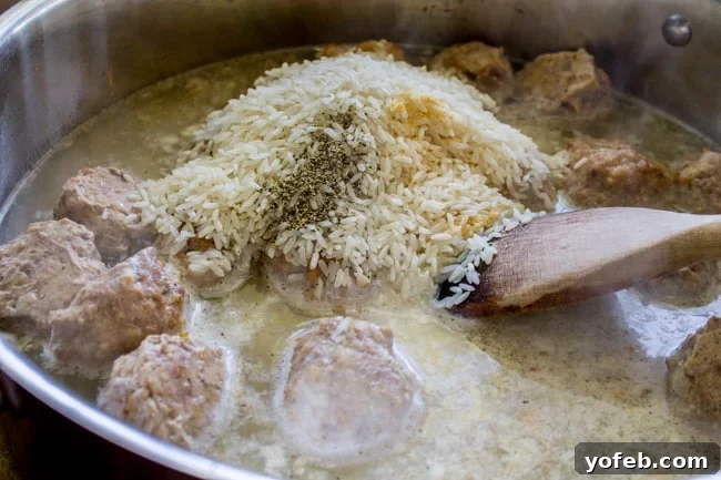 One Pan Meatball Rice Feast 6 Mixing rice, beef broth, seasonings, and meatballs in a skillet.