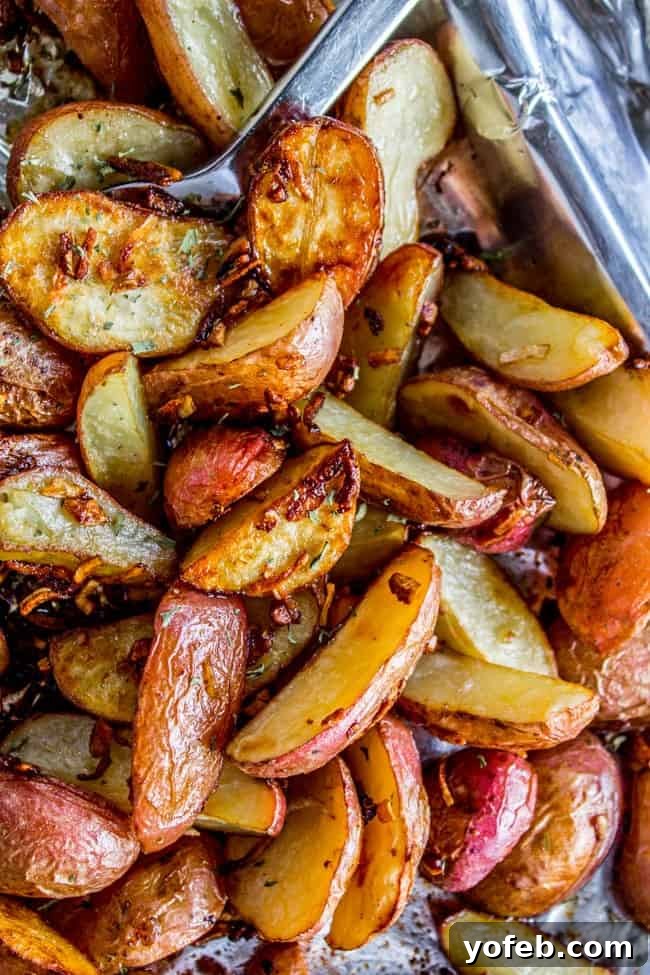 Crispy Roasted Potatoes and Onions on Baking Sheet A close-up of roasted potatoes on a baking sheet, showing the crispy bits of dehydrated onion soup mix clinging to the potato edges.