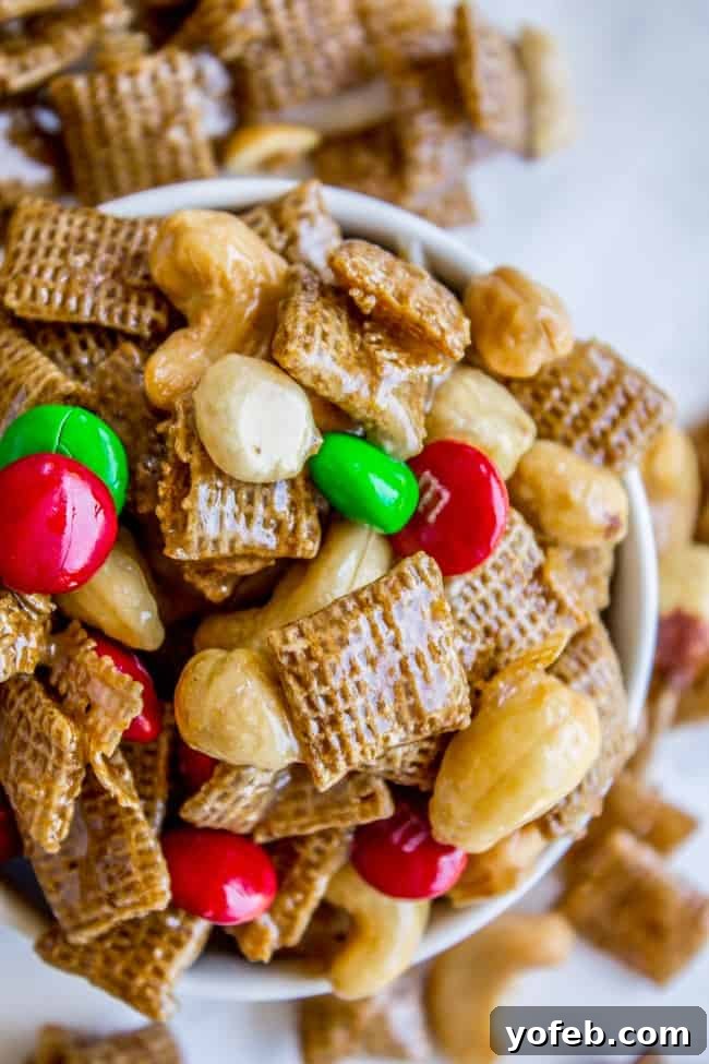 Sticky Sweet-and-Salty Chex Mix (Christmas Crack Recipe) from The Food Charlatan. I've got your yummy Christmas Crack recipe right here! This Sticky Sweet and Salty Chex Mix gets its name for good reason! Once you start you just can't stop. A simple syrup (with LOTS of butter) gets drizzled over corn Chex and studded with nuts and M&Ms. It is salty-sweet perfection! #christmascrack #christmas #chexmix #chex #m&m #sweetandsalty #dessert #yummy #syrup #candy A white bowl filled to the brim with festive Christmas Chex Mix, featuring glistening M&M's and a perfect sweet and salty glaze.