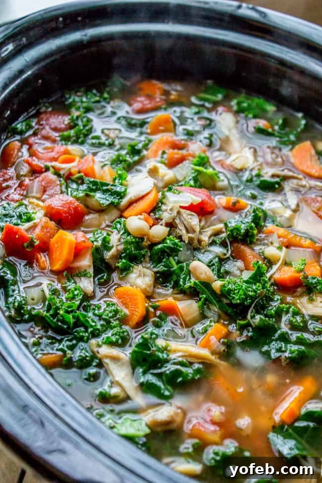 Comforting Slow Cooker Chicken, White Bean, and Kale Soup with Parmesan A vibrant slow cooker filled with hearty chicken, kale, white bean, and Parmesan soup, ready to be served.