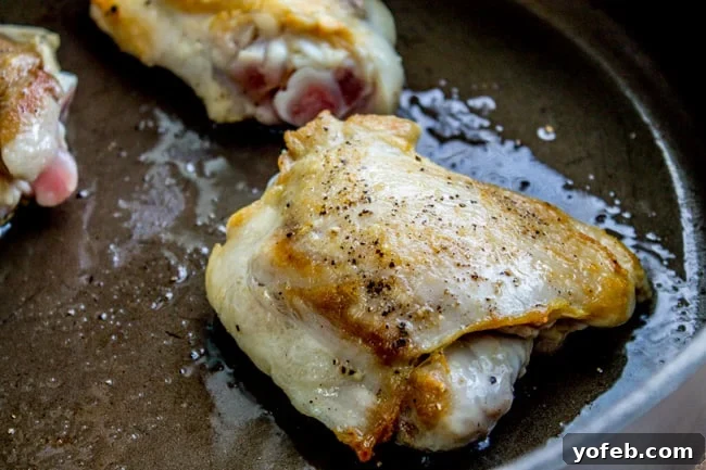 Searing Chicken for Richer Soup Flavor Searing a seasoned chicken thigh in a hot skillet for the slow cooker soup.