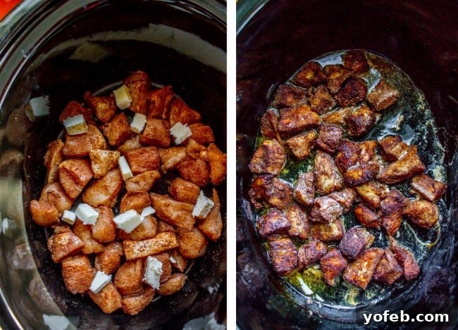 Raw chicken chunks are coated with spices and topped with butter, ready for slow cooking in a crockpot.